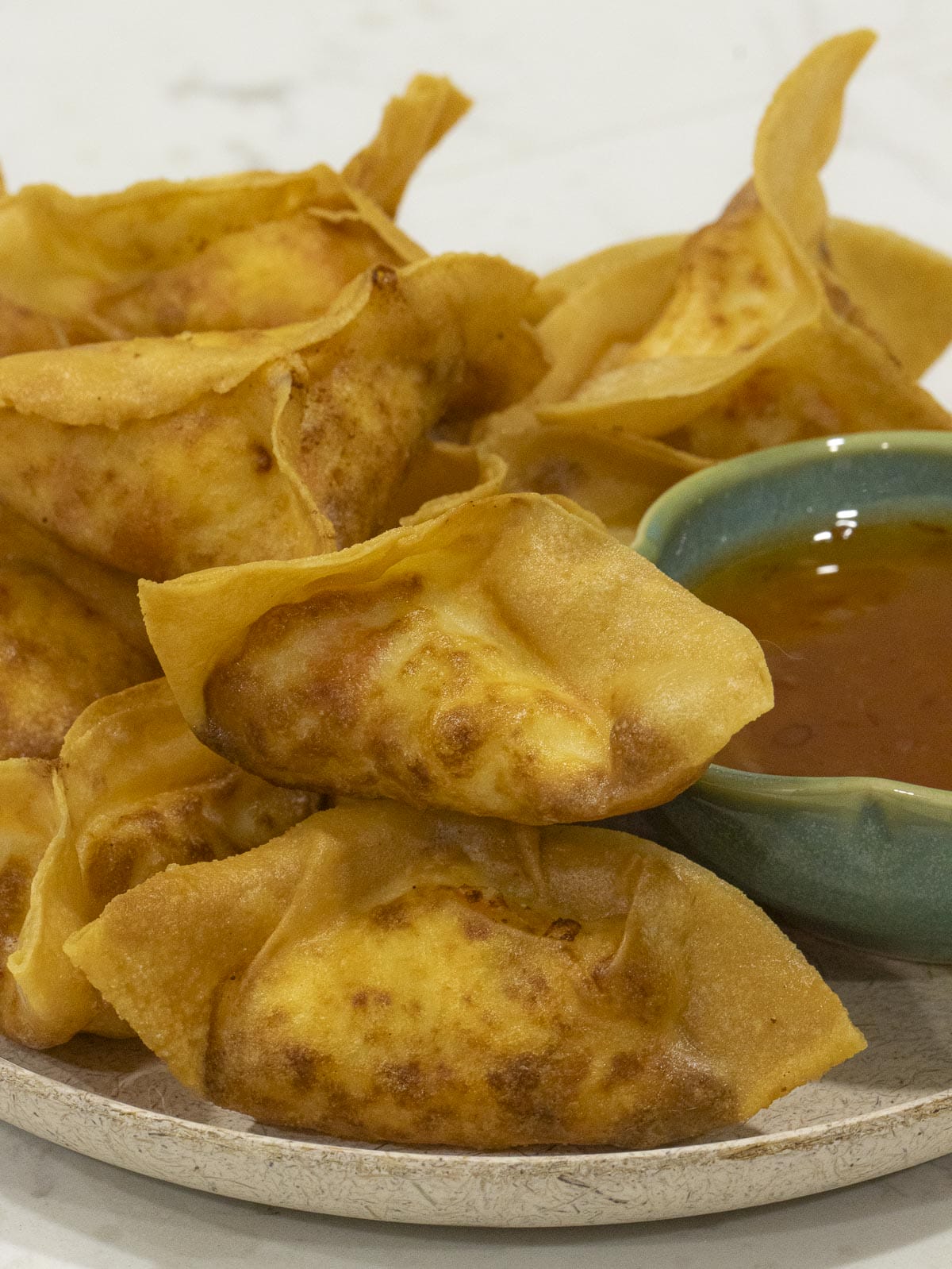 a plate of easy homemade crab rangoons with sweet and chili sauce on the side