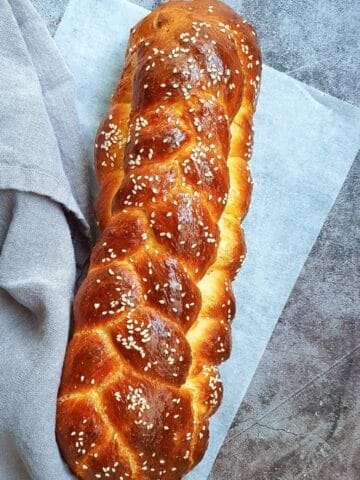 a homemade Challah bread loaf with shiny dark brown crusted topped with sesame seeds
